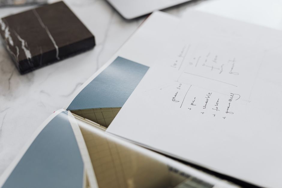 Close-up view of architectural sketches on paper atop a marble desk, showcasing design concepts.